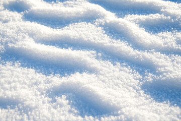 A close-up view of fresh white snow with delicate ripples and soft shadows creating a textured winter landscape in cold light
