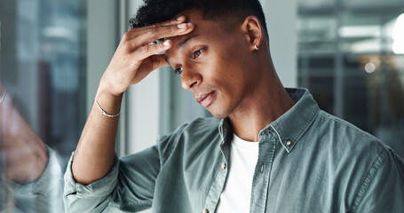 Obraz premium Frustrated, businessman and headache with stress by glass window for mistake, debt or bankruptcy at office. Tired man, employee or fatigue with migraine for financial crisis, tax inflation or loss