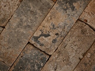 Fototapeta premium A weathered red brick wall with orange hues, showing the rustic pattern of aged bricks and cement, part of an old European university building's historical architecture