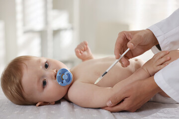 Pediatrician giving injection to cute baby in clinic, closeup