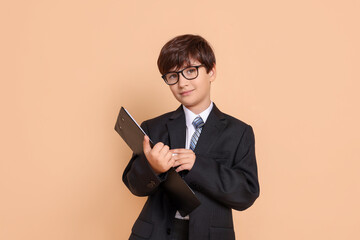 Boy with clipboard pretending to be accountant on beige background. Dreaming of future profession