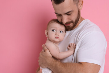 Father with his cute baby on pink background, space for text