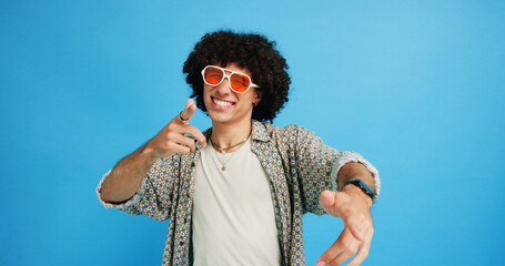 Happy man, portrait and sunglasses with fashion or funky style on a blue studio background. Male...