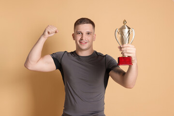 Happy winner with golden trophy cup on beige background