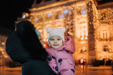  Loving Mother Holding Her Happy Baby Daughter Outdoors in Front of Festive Lights