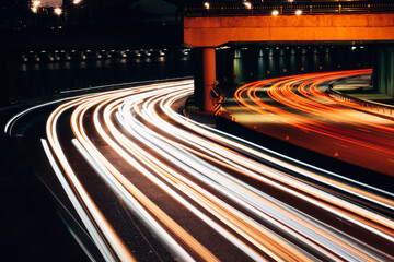 A long exposure of car light trails on a highway, featuring a dramatic tunnel entrance, vibrant streaks.
