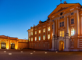 Fototapeta premium Historic building illuminated at dusk near a courtyard with colorful windows showcasing architectural beauty