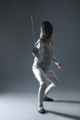 Fencer with epee practicing on gray background