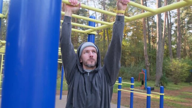 Man doing pull-ups on outdoor bars in a park. Focused, healthy, exercise, workout, active lifestyle, fitness concept