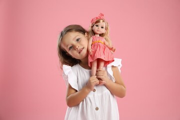 Cute little girl with doll on pink background