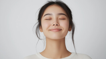 Young asian woman smiling with closed eyes and relaxed expression.  Ideal for promotions or ads