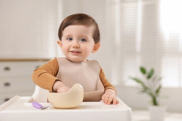 Cute little baby eating healthy food from bowl in high chair at home, space for text