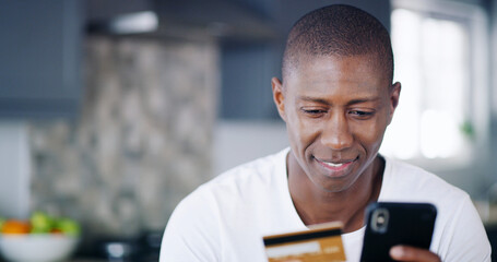 Black man, credit card and phone purchase in home, wireless transaction and online shopping. Male person, banking website and ecommerce for checkout order, payment and kitchen for finance money app