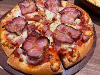 Pizza with prosciutto (parma ham) on dark wooden background top view. Italian cuisine. Space for text.