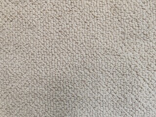Close-up texture of a beige loop-pile carpet, featuring a soft and detailed woven pattern. Ideal for backgrounds, interior design concepts