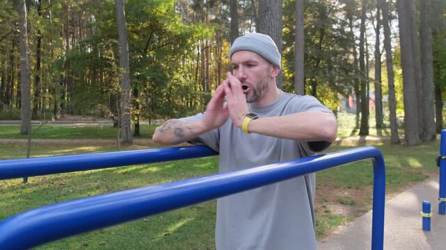 Man warming up on parallel bars, outdoors. Trees in the background. Fitness training