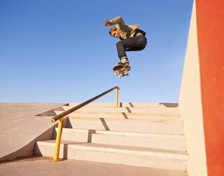 Freedom, fitness and man with skateboard, jump or rail balance at skate park for steps stunt training. Energy, adrenaline and gen z male skater with air, sports or stairs, exercise and performance