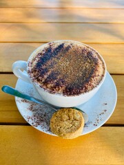 A white cup of coffee and cookie on the wooden table 