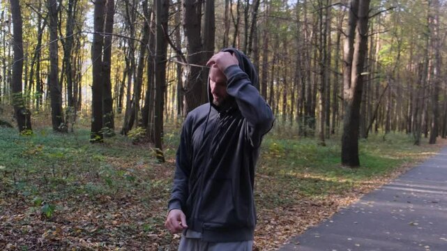 A man is running along a forest path on a sunny autumn day
