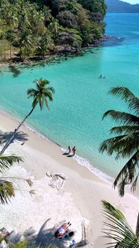 Experience the serene shores of Koh Kood Island where crystal-clear waters meet soft, sandy beaches. Relax under swaying palms while soaking in the sun, a couple on vacation in Thailand