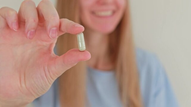 Close-up of one iron capsule in a woman's hand. Medicines and dietary supplements
