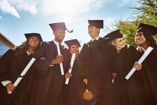 Graduation, low angle and education with students in college for diploma, scholarship and future. University degree, certificate and achievement with people in outdoor for diversity, friends or event