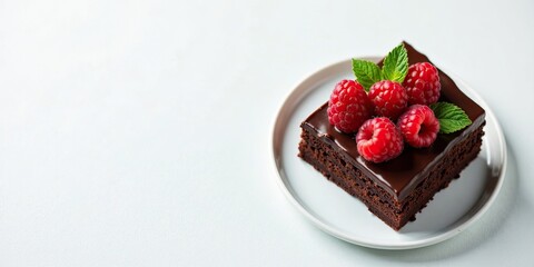 A delectable chocolate dessert, rich and fudgy, adorned with fresh raspberries and a sprig of mint, served on an elegant plate.