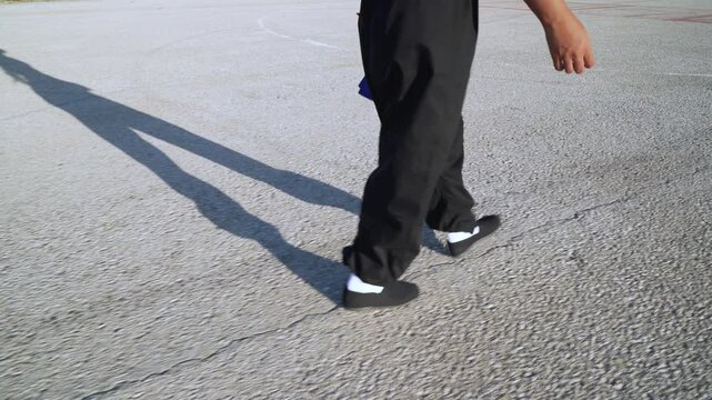 Chica luchadora de artes marciales caminando por el asfalto de una pista de aterrizaje un d&iacute;a soleado. como concepto de perseguir tu camino o destino.