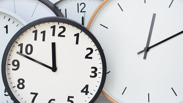 a collection of overlapping analog clocks, each with a clean and minimalistic design. The clocks have white faces with black hour and minute markings, and black or wooden frames. 