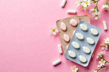 Blister packs on textured pink background with scattered white flower capsules and small white flowers in a floral arrangement, medication, drug, medicine