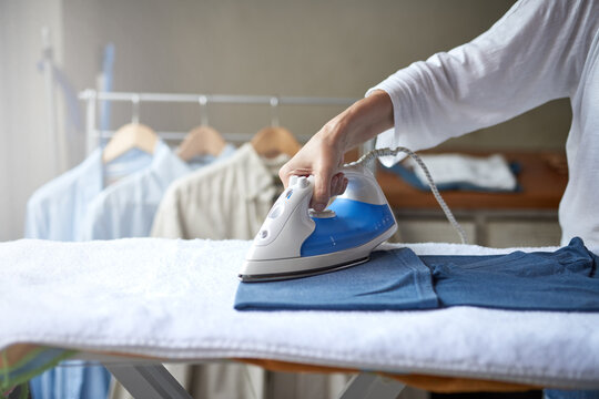 Woman, chores and ironing with shirt at home for responsibility of clean laundry for husband. Female person, help and household by cleaning clothes for hygiene, work and care as reliable housewife