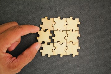 The puzzles are arranged and the hand holds the last puzzle for combination. concept of solution or...