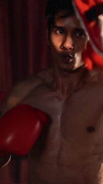 Asian and Caucasian Muay Thai boxer unleash punch in fierce boxing training session, delivering punching strike to sparring trainer, showcasing Muay Thai boxing technique and skill. Impetus