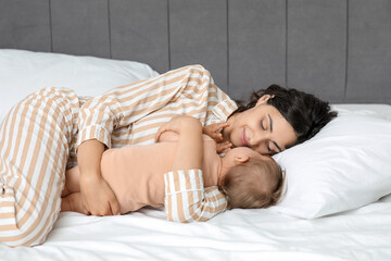 Happy mother with her little baby lying on bed at home