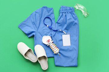 Medical supplies with uniform and shoes on green background. Top view