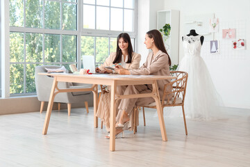 Female wedding planners working with laptop at table in office