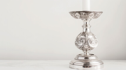 A polished metal candlestick holder with an ornate design on a white background with copy space.