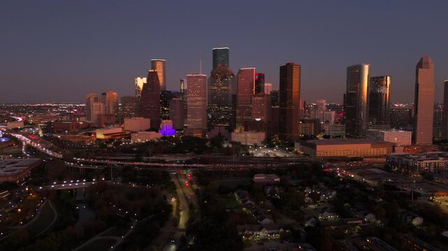 Breathtaking aerial view of Houston, Texas, highlights the stunning downtown skyline illuminated at twilight, creating a captivating atmosphere with vibrant, colorful lights and stunning purple sky