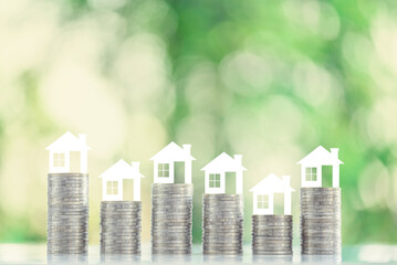 Mortgage loan or home equity loan, financial concept : Tiny model residential house perched atop coin stacks, depicting home loan or borrowing money to purchase a new home for first time homebuyer.