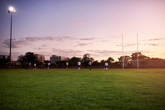 Men, team and rugby player for outdoor, sports and challenge in exercise, wellness and fitness. Male people, athlete and recreation facility at sunset for match, game and training in stadium or arena