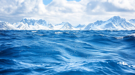 Snow-capped mountains rise above deep blue ocean waves in a remote winter landscape