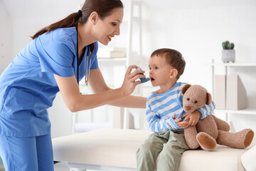 Female pediatrician giving inhaler to cute little boy in clinic