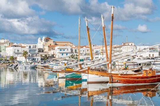 Colorful wooden boats are reflected in the water of the port of Calasetta, Sant'Antioco, Italy