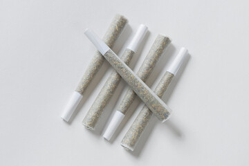 Five pre-rolled marijuana joints on white background