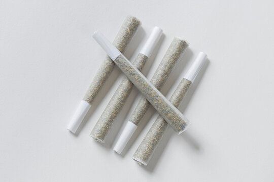 Five pre-rolled marijuana joints on white background