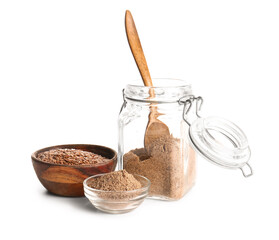 Wooden bowl of flax seeds and jar of flour on white background