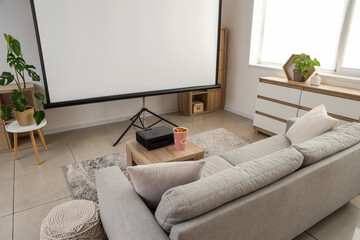 Interior of stylish living room with grey sofa, popcorn and modern projector on coffee table