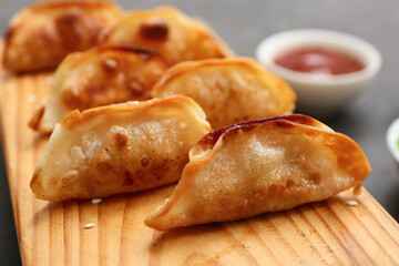 Wooden stand with fried Japanese gyoza on black background, closeup