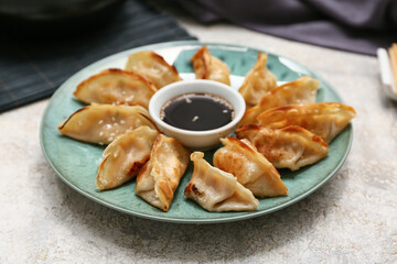 Plate with fried Japanese gyoza and bowl of soy sauce on white background, closeup