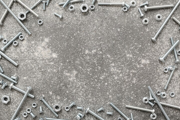Frame made from different tap bolts and chrome nuts on grey grunge background